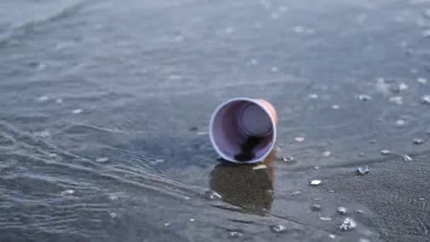 Vrouw neemt af plastic beker van oceaan strand met stenen — Stockvideo