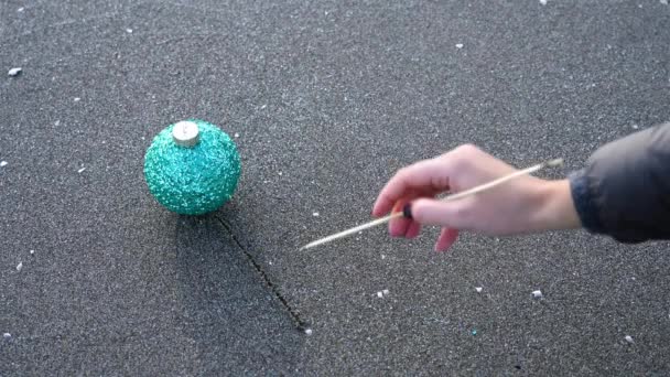 Жінка малює ялинку з зеленим м'ячем на мокрій піску — стокове відео