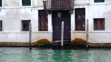 Eski siyah metal kapının üstünde paslı balkon olan eski bir ev.