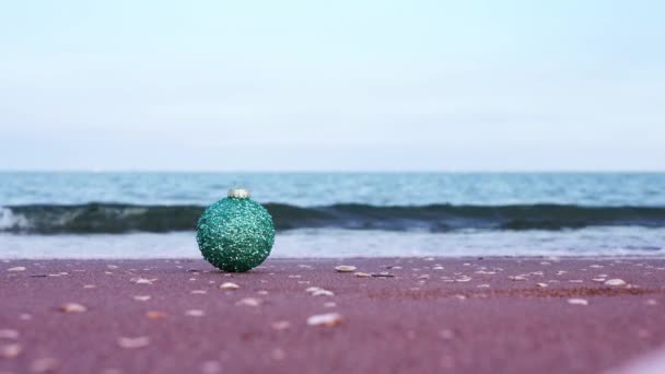 Dekorativ julgran boll med glitter på våt sand — Stockvideo