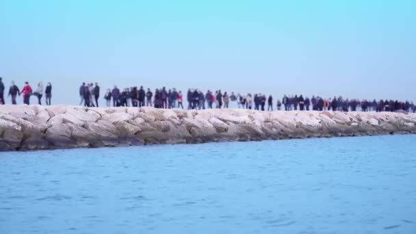 Lidé v maskách chodí po skalnatém molu poblíž azurového oceánu — Stock video
