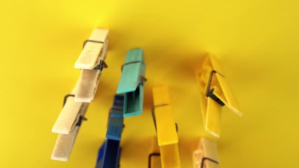Σύνολο από πλαστικό χρώμα ρούχα μανταλάκια στέκεται στο φωτεινό κίτρινο — Αρχείο Βίντεο
