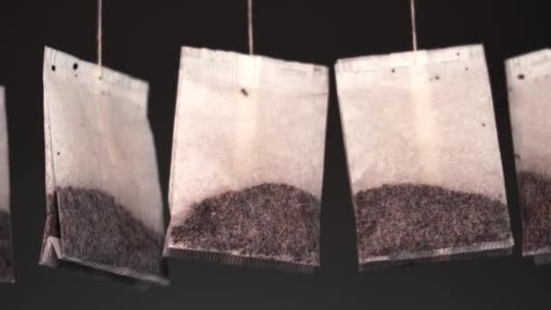 Сваренный вкусный травяной чай мешки висят размахивая на темном фоне — стоковое видео