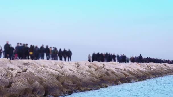 Lidé chodí podél dlouhého skalnatého mola poblíž klidného azurového oceánu — Stock video