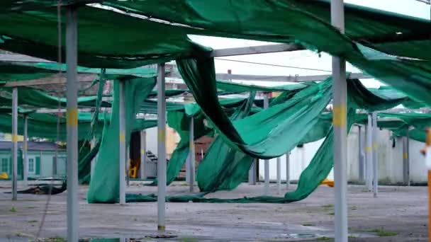 Estacionamento material de cobertura rasgado pelo vento encontra-se no chão por garagem — Vídeo de Stock