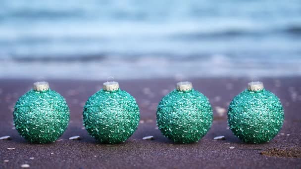 Bolas de árbol de Navidad verde brillante en la playa del mar vista cercana — Vídeos de Stock