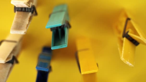 Різні кольорові пластикові шпильки для одягу, що стоять на жовтому — стокове відео