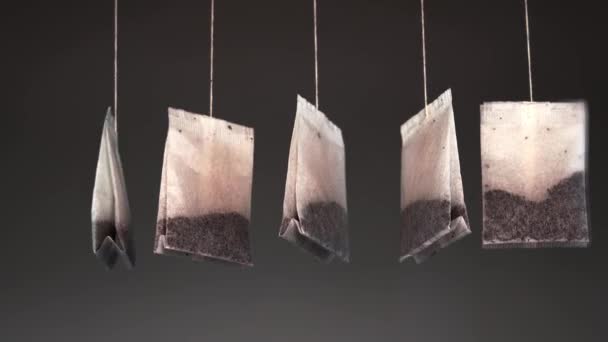 Schlange von aufgebrühten leckeren Teebeuteln an Fäden hängt im dunklen Raum — Stockvideo