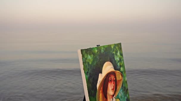Canvas z portretem dziewczyny w kapeluszu trzymającej kotka na plaży — Wideo stockowe