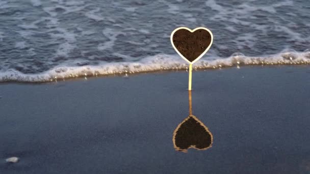 Deska ve tvaru srdce s kapkami a odrazem na mokrém písku — Stock video