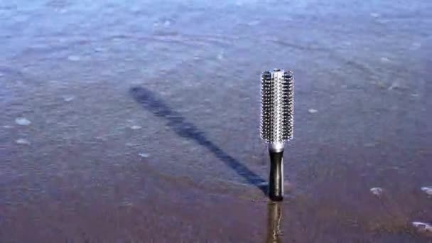 Cepillo de pelo de plástico se queda atascado en la arena lavado por olas — Vídeos de Stock