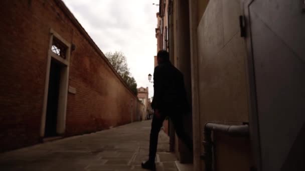 ノートパソコンを持つ男は小さなヴェネツィアの狭い通りに沿って実行されます — ストック動画