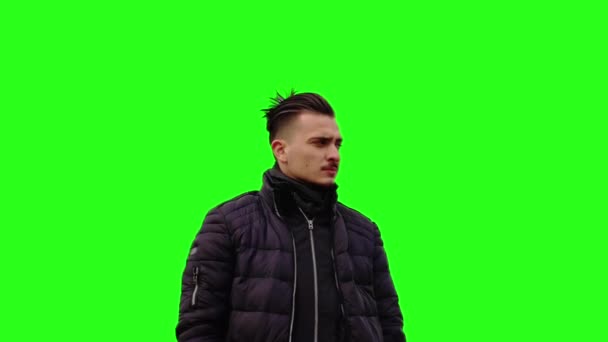 Young man in black jacket crosses arms on green chromakey — 图库视频影像