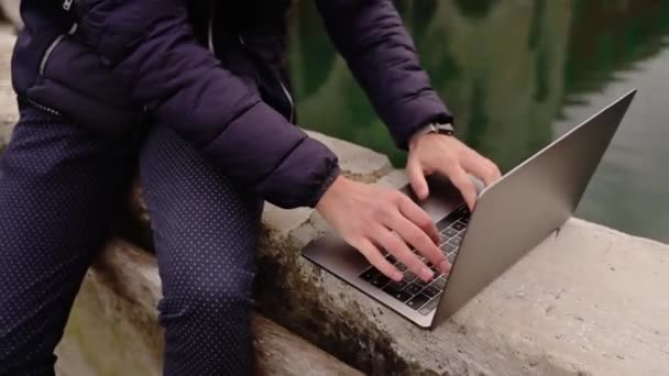 Man with mustache works on laptop sitting on bridge parapet — Vídeo de Stock