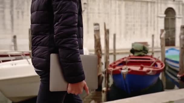 Man loopt met laptop op kanaal dijk langs boten — Stockvideo