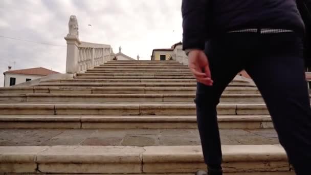 Guy with modern laptop goes up marble steps of old bridge — Vídeo de Stock
