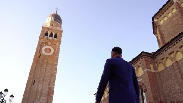 Chico con estilo en abrigo azul profundo camina en la antigua calle de la ciudad — Vídeos de Stock