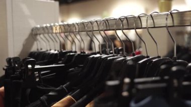 Butikte siyah plastik askıları olan uzun metal bir kalas.