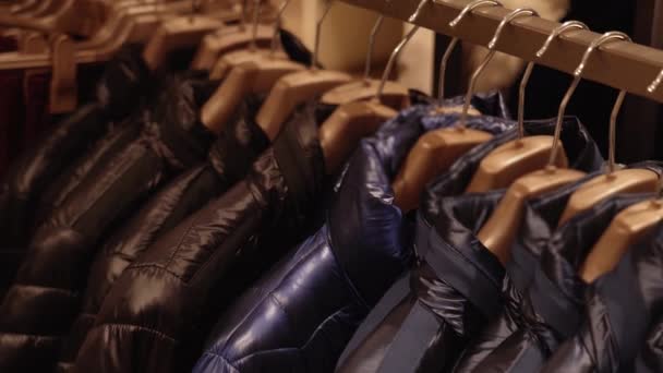 Jesienne kurtki wiszące na drewnianych wieszakach w butiku mody — Wideo stockowe
