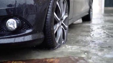 Modern siyah otomobil sel suları arasında duruyor.