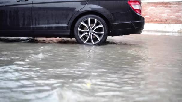 Voda zaplavená ulice a parkoviště s moderním černým autem — Stock video