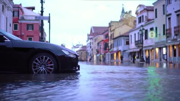 Carro preto moderno fica entre a água da inundação correndo na rua — Vídeo de Stock