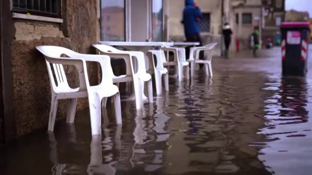 Вуличне кафе стоїть серед брижі води після припливної повені — стокове відео