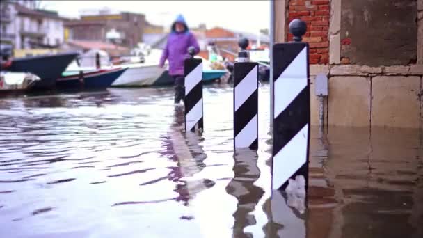 Homme en bottes spéciales en caoutchouc marche le long de la rue inondée — Video