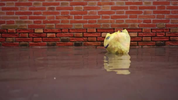 塑料袋漂浮在经过砖楼的洪水之上 — 图库视频影像