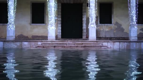 Будівля, прикрашена казковими вогнями, відбивається у воді — стокове відео