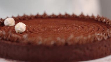 Kadın çikolatalı turtayı beyaz şekerlerle süslüyor.