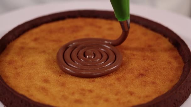 Putting chocolate filler spiral on traditional tart on stand — Stock Video