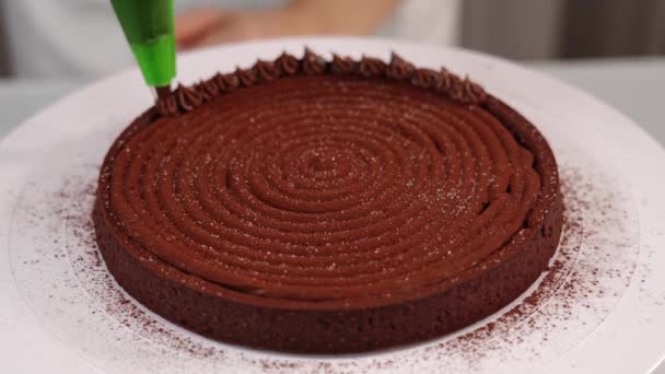 Suikerbakker versiert taart met chocolade crème op standaard — Stockvideo