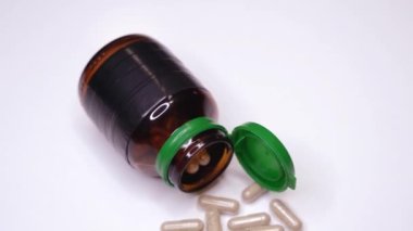 Hapların yanında yeşil başlıklı cam ilaç şişesi var.