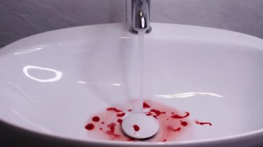 Beyaz, parlak banyo lavabosu ve korkutucu kırmızı kan pıhtıları.