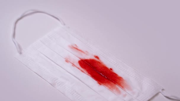 Λευκή προστατευτική ιατρική μάσκα με κηλίδες αίματος στο τραπέζι — Αρχείο Βίντεο