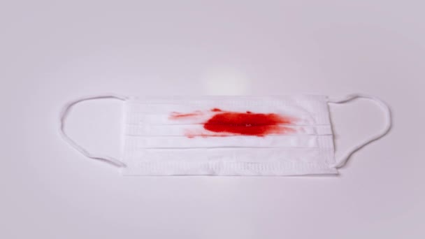 Medizinische Maske mit rotem Blutfleck, den ein Kranker hinterlassen hat — Stockvideo