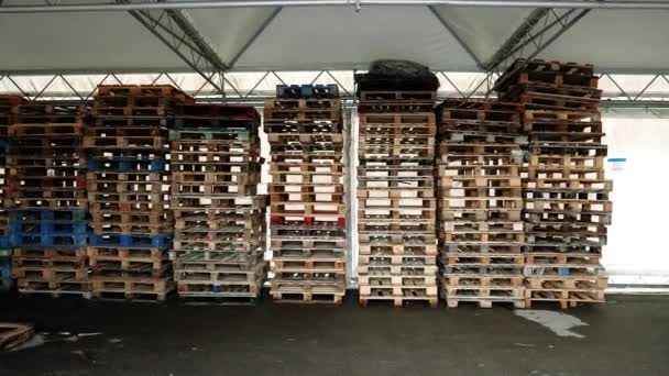 Motion to stacks of wooden pallets in light warehouse — Stock Video