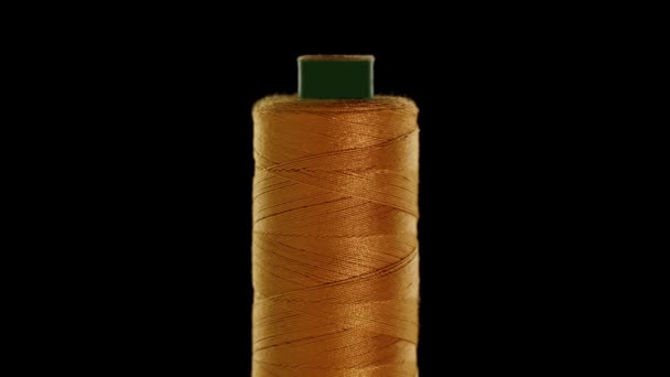 Gold colored sewing thread on a black background — Stock Video
