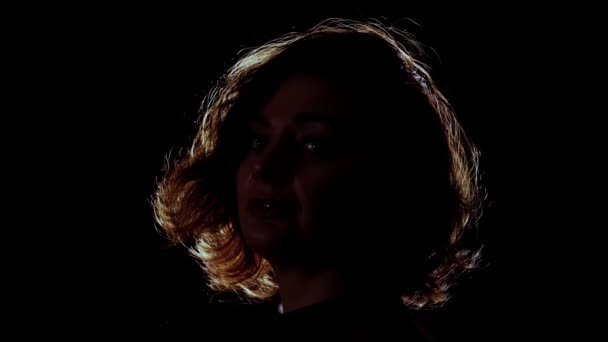 Mulher Languid com cabelo encaracolado posa para câmera em preto — Vídeo de Stock