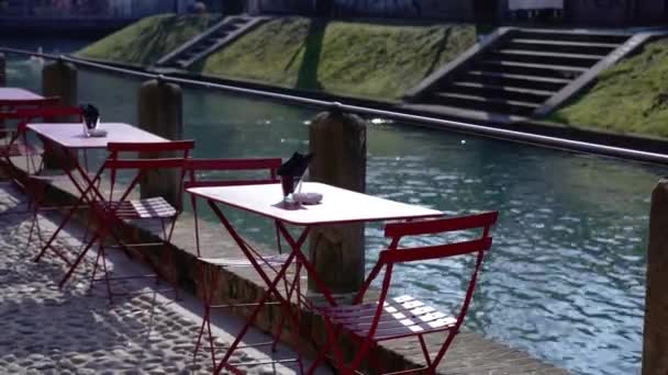 Mese proiectate de cafenea și scaune roșii localizate pe malul canalului — Videoclip de stoc