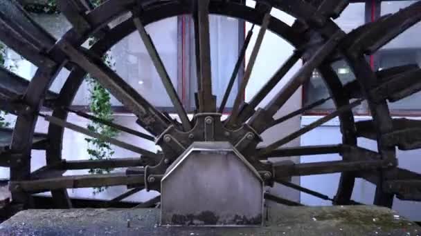 Nagy öreg vízimalom sötét fém kerék forog házról házra — Stock videók