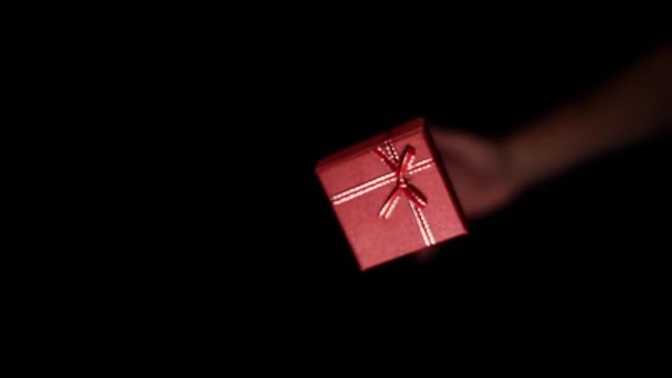 Рука человека бросает вверх небольшую бумажную красную коробку с лентой — стоковое видео