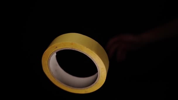 Rolo de fita adesiva amarela com centro branco gira em preto — Vídeo de Stock