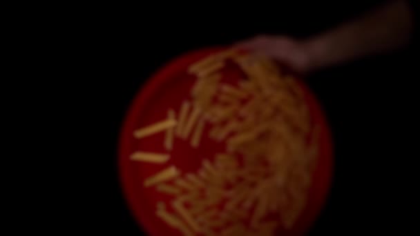 Personenhände werfen trockene gelbe Penne-Pasta von rotem Teller hoch — Stockvideo