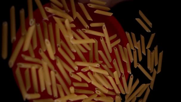 Trockene Penne-Pasta fällt unter elektrischem Licht auf roten Teller — Stockvideo