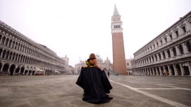Kadın elinde elbise tüyü tutarak ünlü boş meydanda yürüyor
