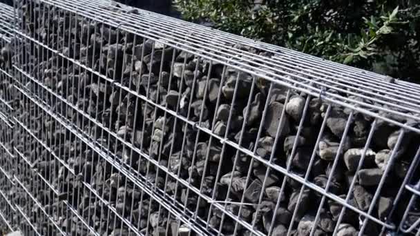 Baharda metal şebeke kafesinde gri taşlarla tasarlanmış çit. — Stok video