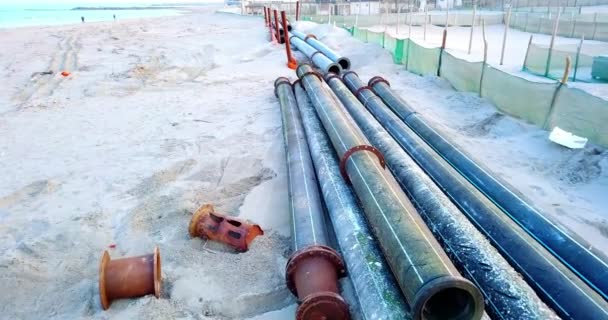 Drainage pipe laying surrounded by litter on sandy beach — Stock Video