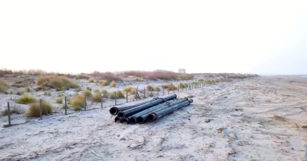 Pipa logam hitam yang terbengkalai terletak di pantai di bukit pasir yang lebat — Stok Video